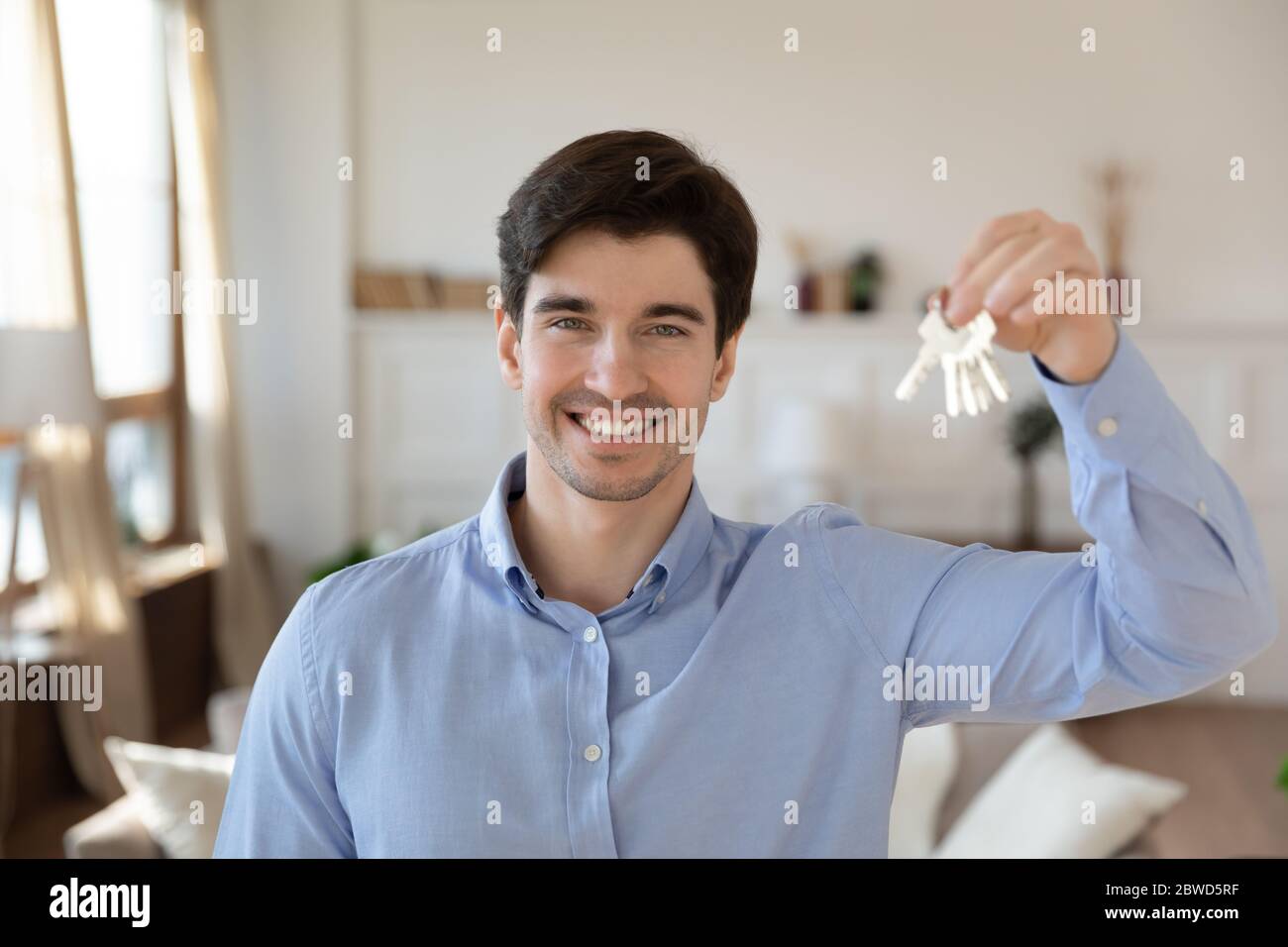 Portrait des glücklichen männlichen Mieter zeigen Schlüssel zu eigenem Haus Stockfoto