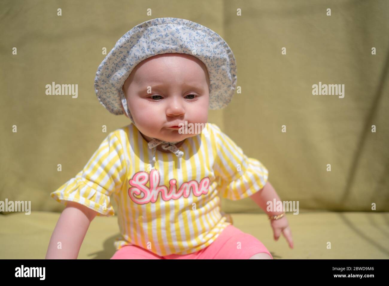 Nettes Baby Mädchen tragen liebenswert Hut suchen Kamera machen lustige Gesichter auf grünem Hintergrund Stockfoto