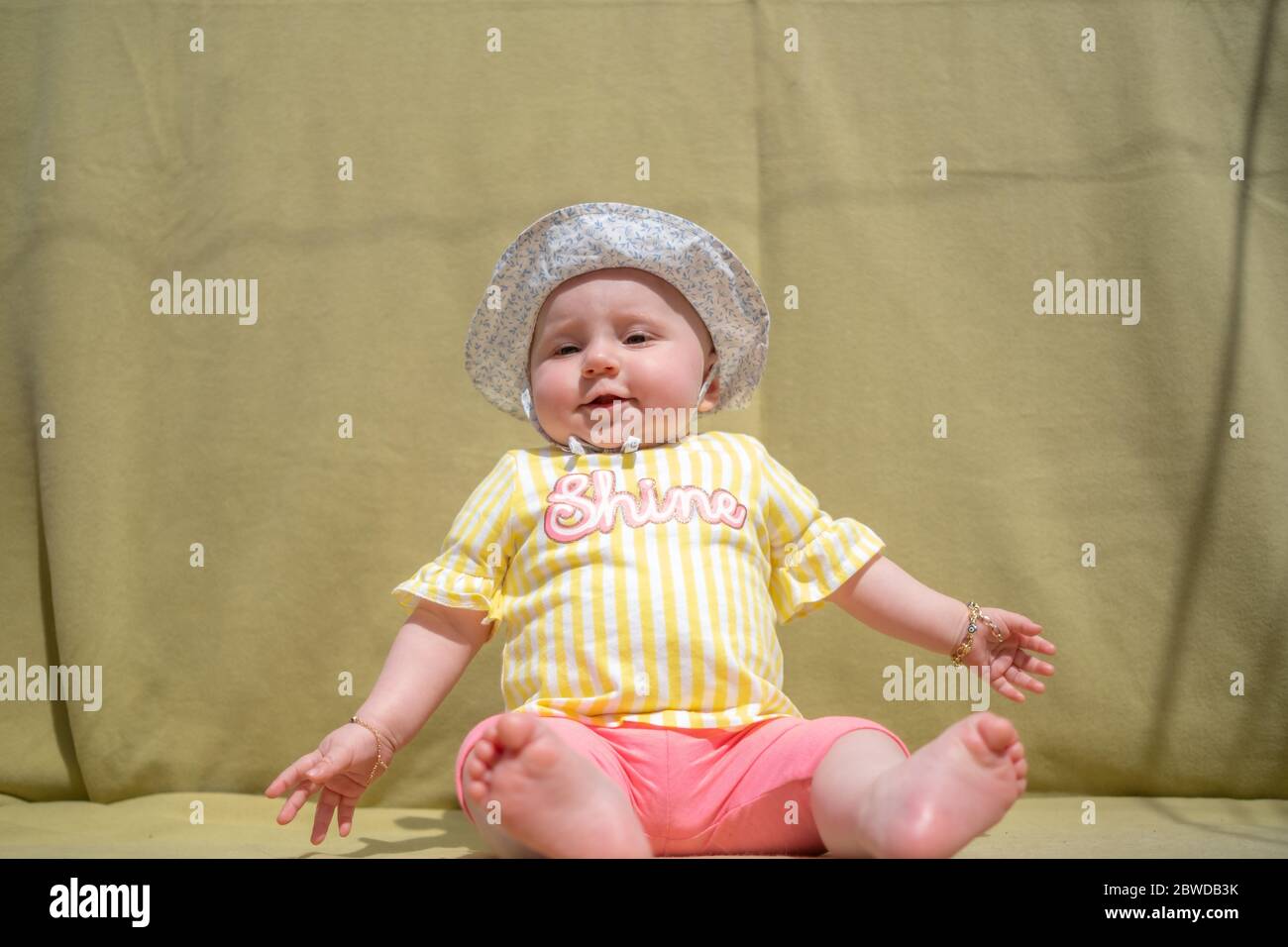 Nettes Baby Mädchen tragen liebenswert Hut suchen Kamera machen lustige Gesichter auf grünem Hintergrund Stockfoto