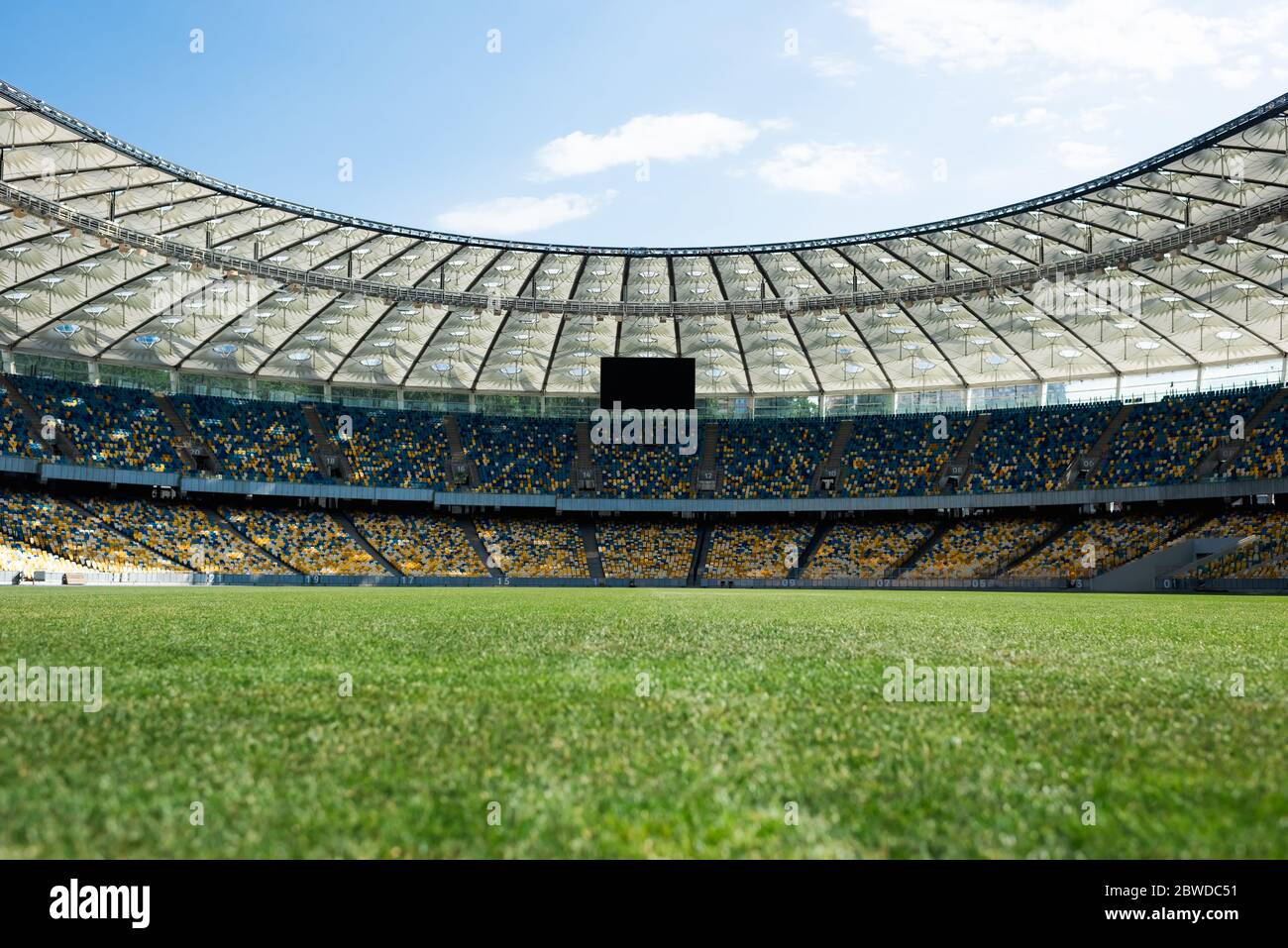 Rasenfußballplatz im Stadion bei sonnigem Tag mit blauem Himmel Stockfoto