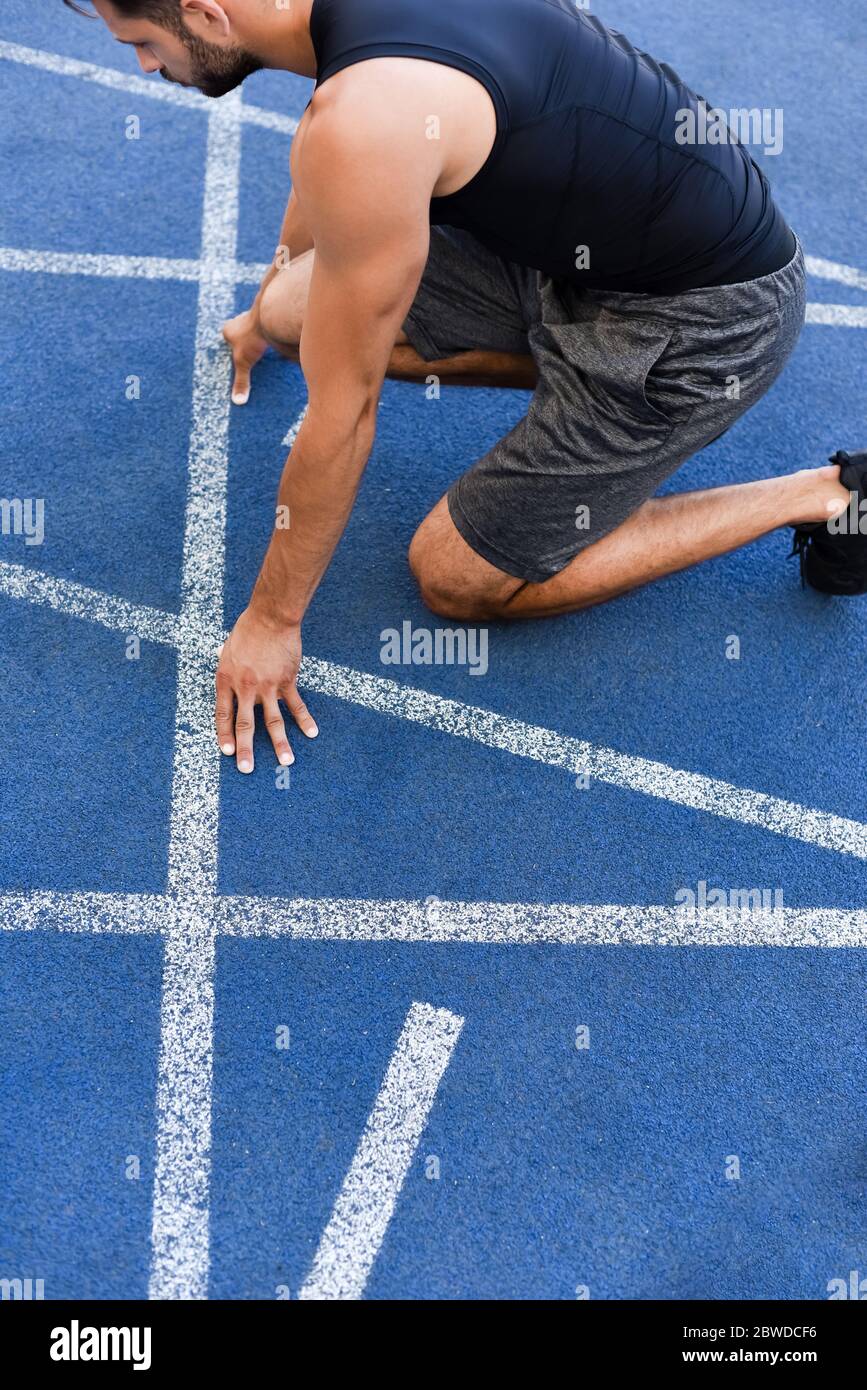 Verkürzte Ansicht des Läufers in Startposition auf der Laufstrecke im Stadion Stockfotografie Verkürzte Ansicht des Läufers in Startposition auf der Laufstrecke im Stadion Stockfotografie