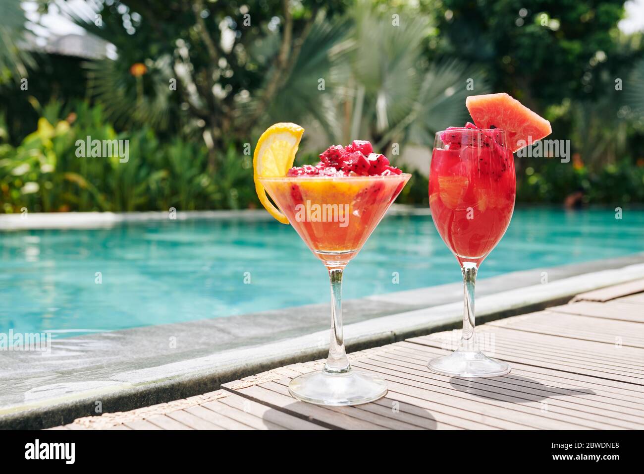 Zwei Gläser mit roten Drachenfrüchten und Grapefruit-Smoothie am Rande des Swimmingpools Stockfoto
