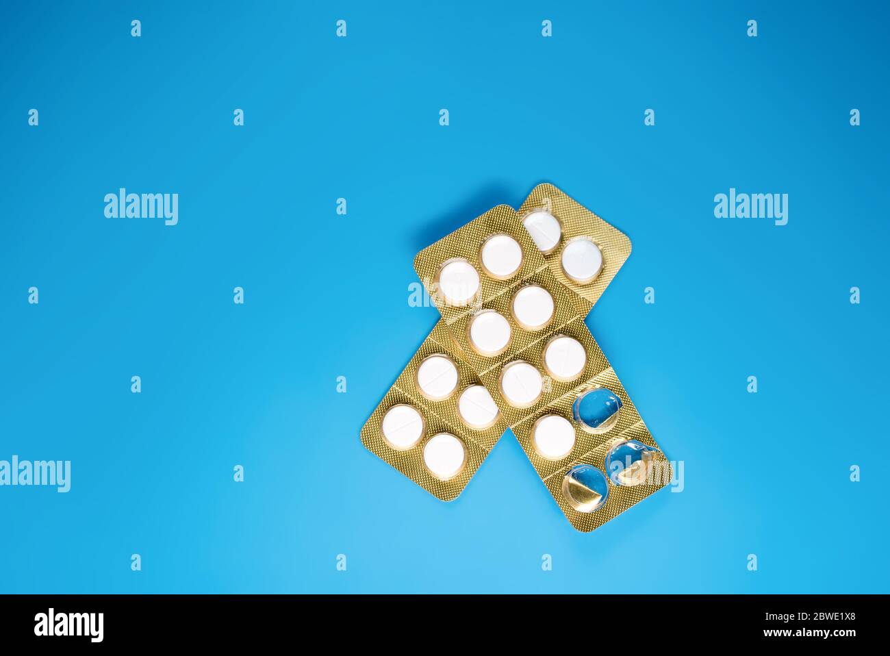 Eine offene weiße Pille und eine versiegelte Packung mit blauem Hintergrund Stockfoto
