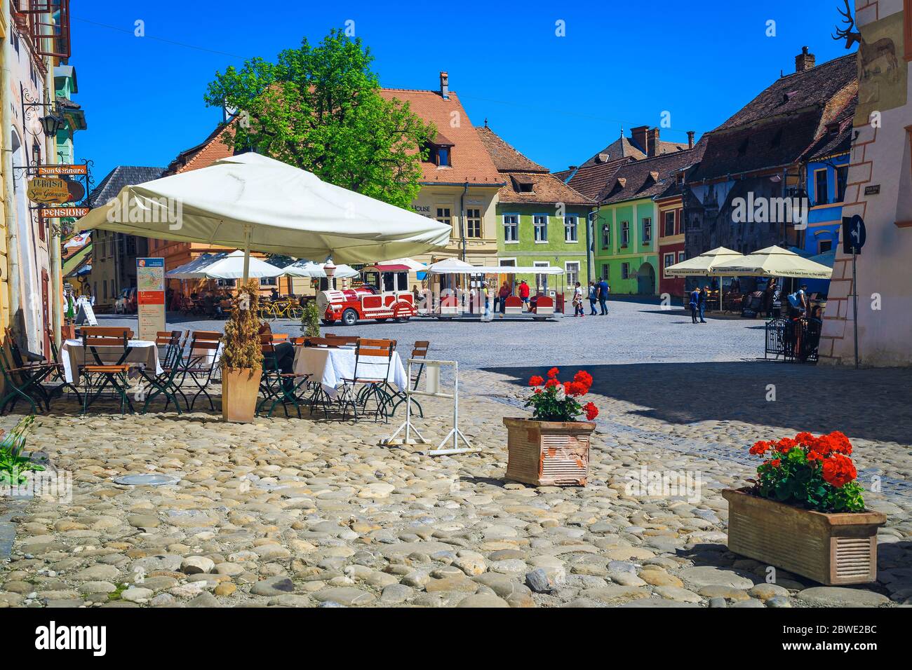 SIGHISOARA, RUMÄNIEN - 21. APRIL 2018: Am besten besuchte Siebenbürgen Stadt und Altstadt Promenade mit Straßencafees. Touristenzug im Stadtzentrum, Sig Stockfoto