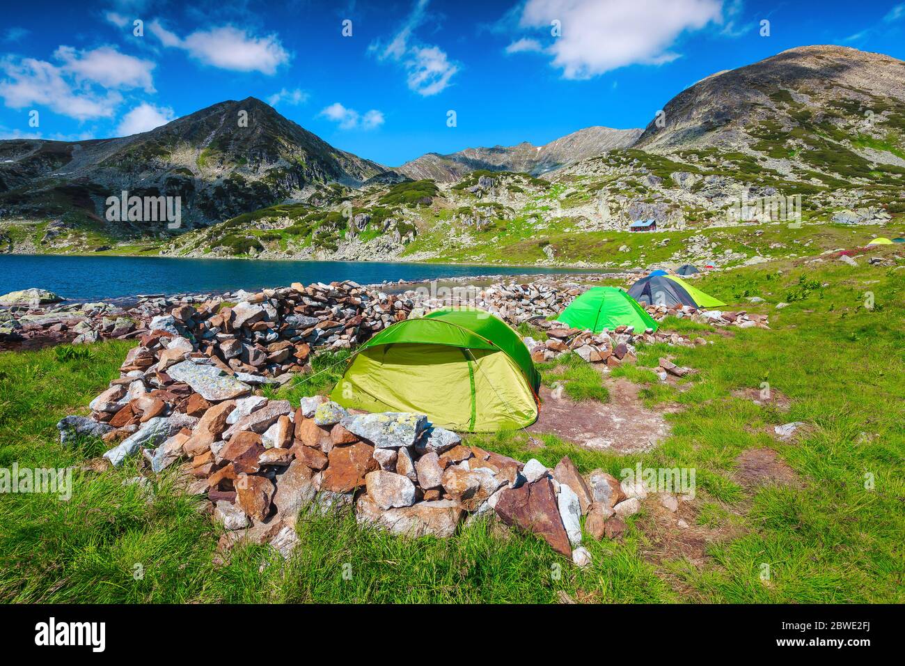 Schöner alpiner Campingplatz mit bunten Zelten am Ufer des Bucura Sees. Malerischer Bergcamping im Naturpark Retezat, Karpaten, Stockfoto