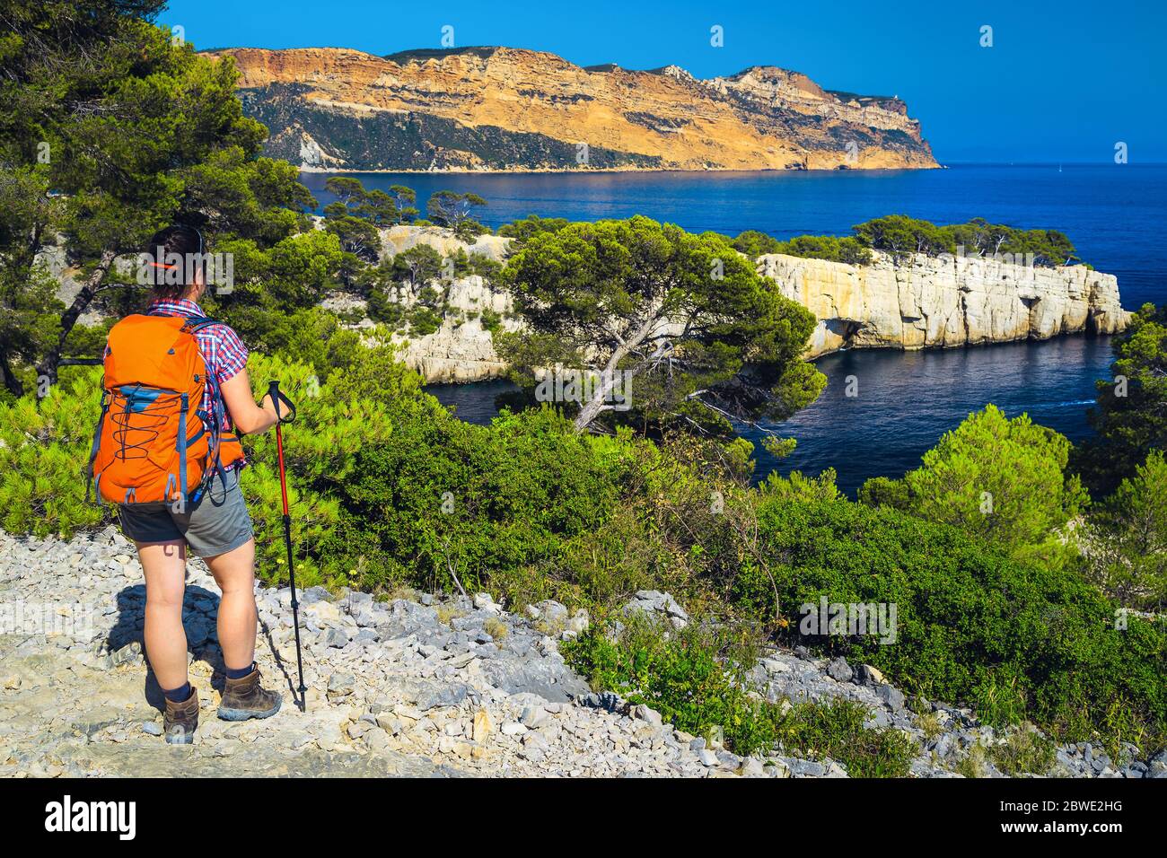 Sportliche Wandererin mit Rucksack, die die Aussicht mit der blauen Wasserbucht vom Wanderweg im Calanques Nationalpark, Cassis, Provence, Frankreich, EUR genießt Stockfoto