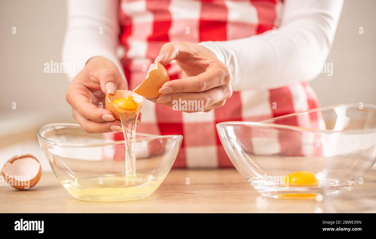 Detail der Hände der Frau, die Eigelb vom Weißen in zwei Glasschüsseln trennt Stockfoto