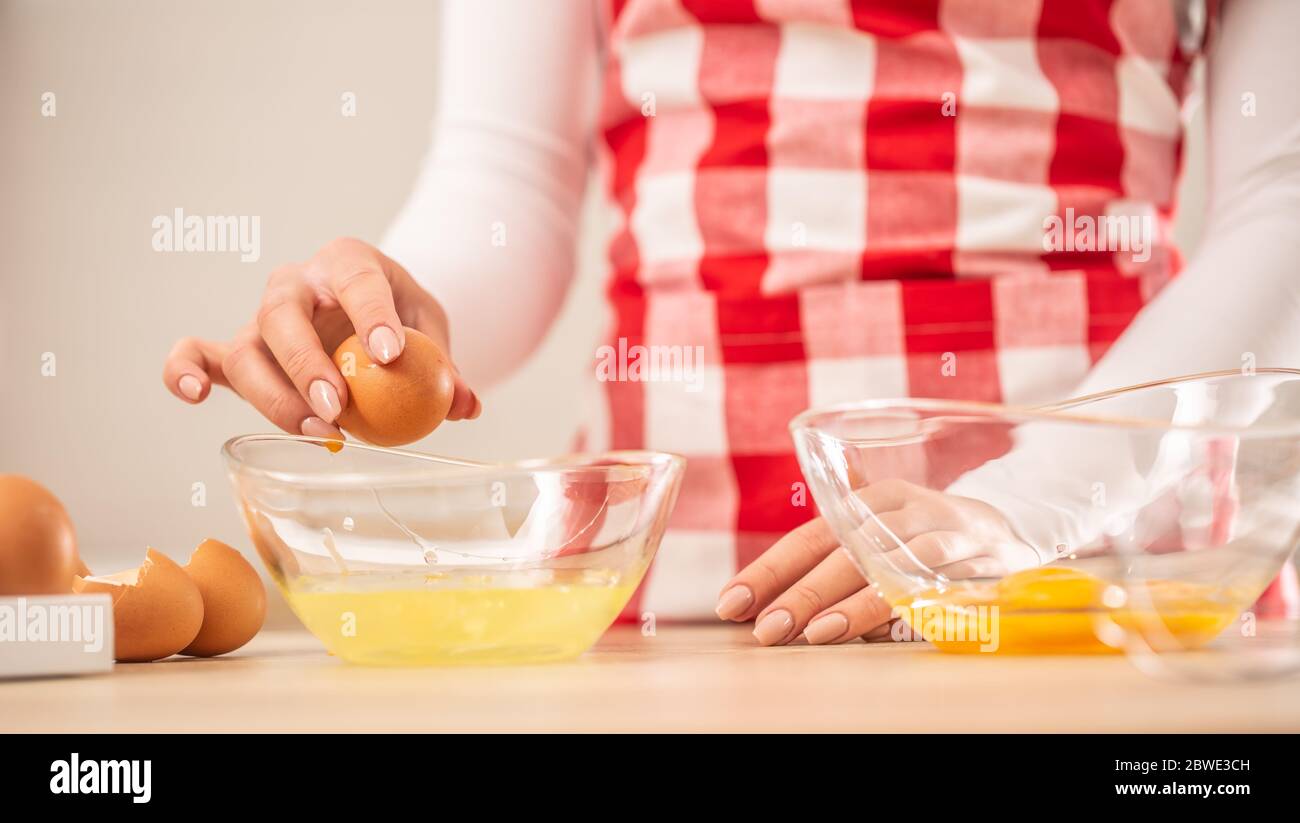 Detail der Hände der Frau, die Eigelb vom Weißen in zwei Glasschüsseln trennt Stockfoto
