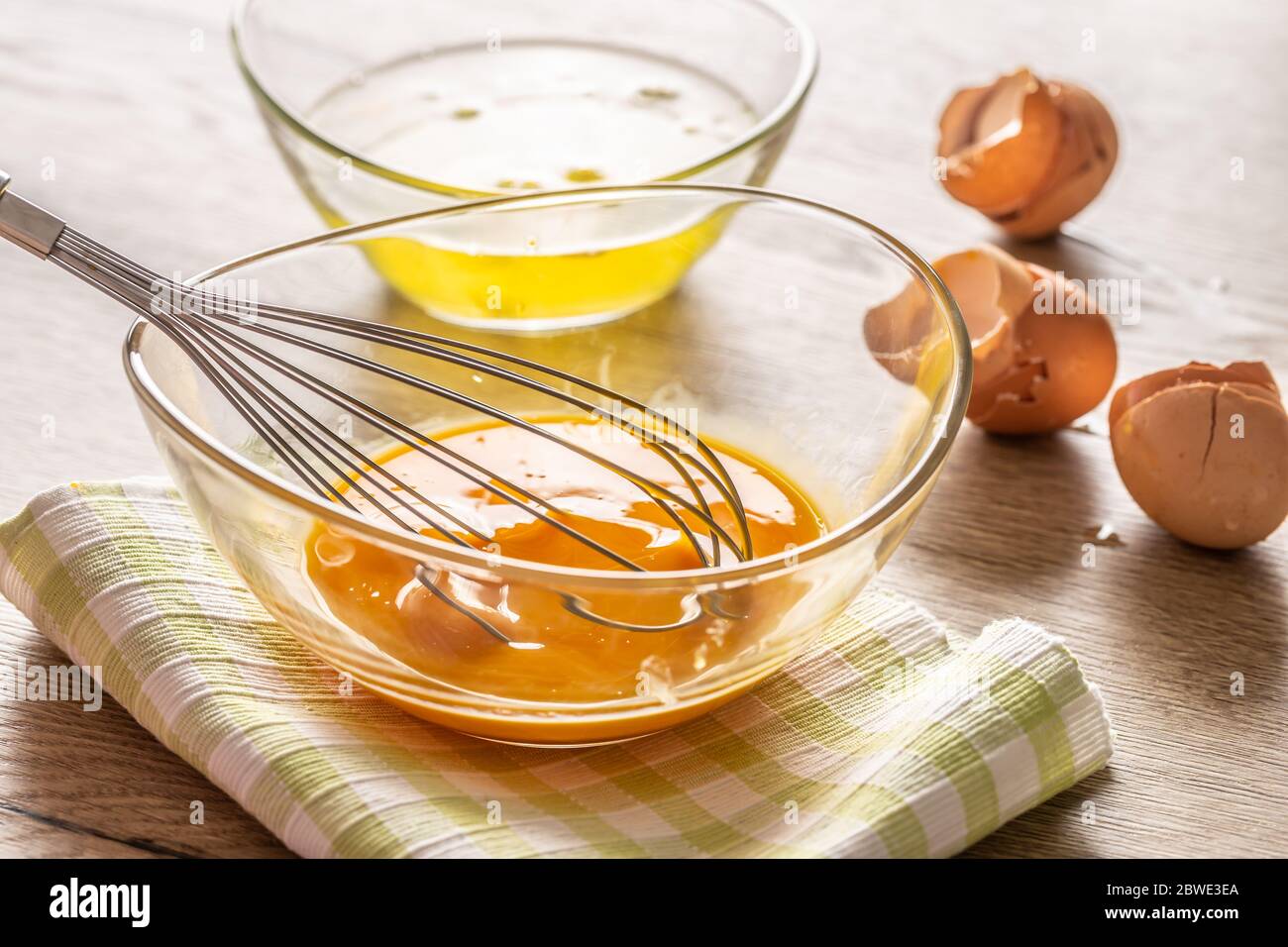 Eigelb in einer Glasschüssel mit Eiweiß in einer zweiten Schüssel und geschruttelten Eierschalen an der Seite geschlüpft Stockfoto