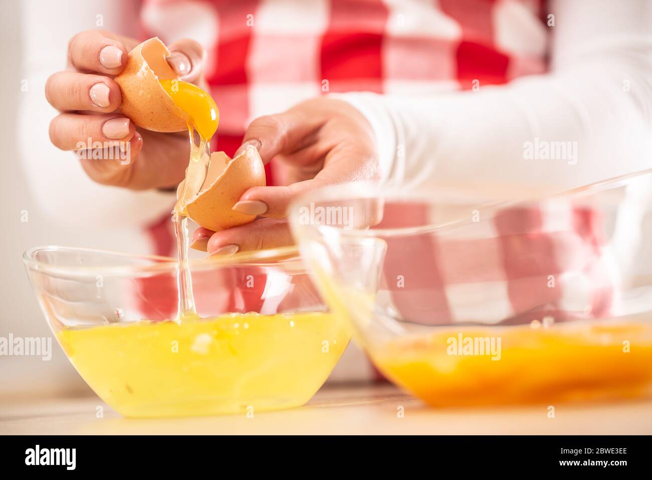 Detail der Hände der Frau, die Eigelb vom Weißen in zwei Glasschüsseln trennt Stockfoto