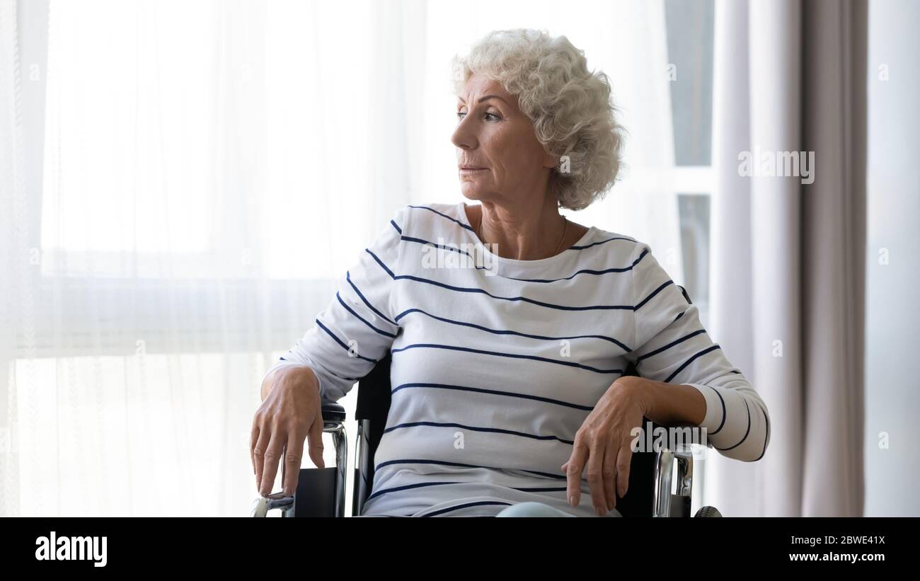Traurig depressiv ältere Frau sitzt im Rollstuhl zu Hause