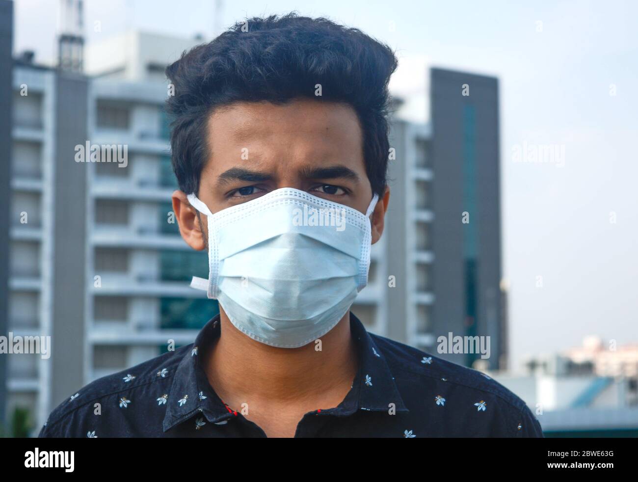 Porträt des jungen Mannes trägt chirurgische Gesichtsmaske auf einem Hintergrund der Corporate Company.Corona Virus, Quarantäne. Stockfoto