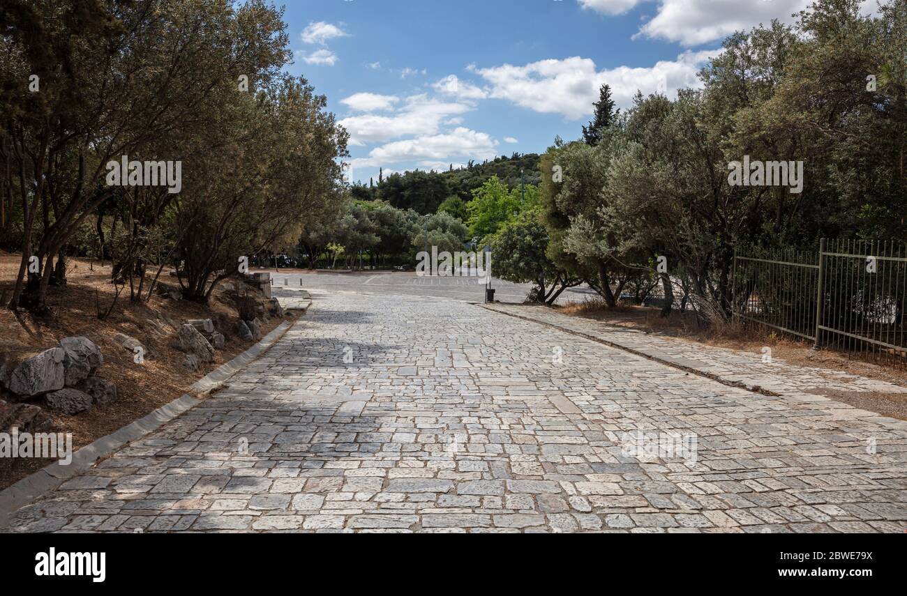 Athen, Griechenland. Kopfsteinpflaster Weg von der Akropolis zur Areopagitou Straße, griechische Flora, blauer Himmel in einem sonnigen Frühlingstag. Stockfoto