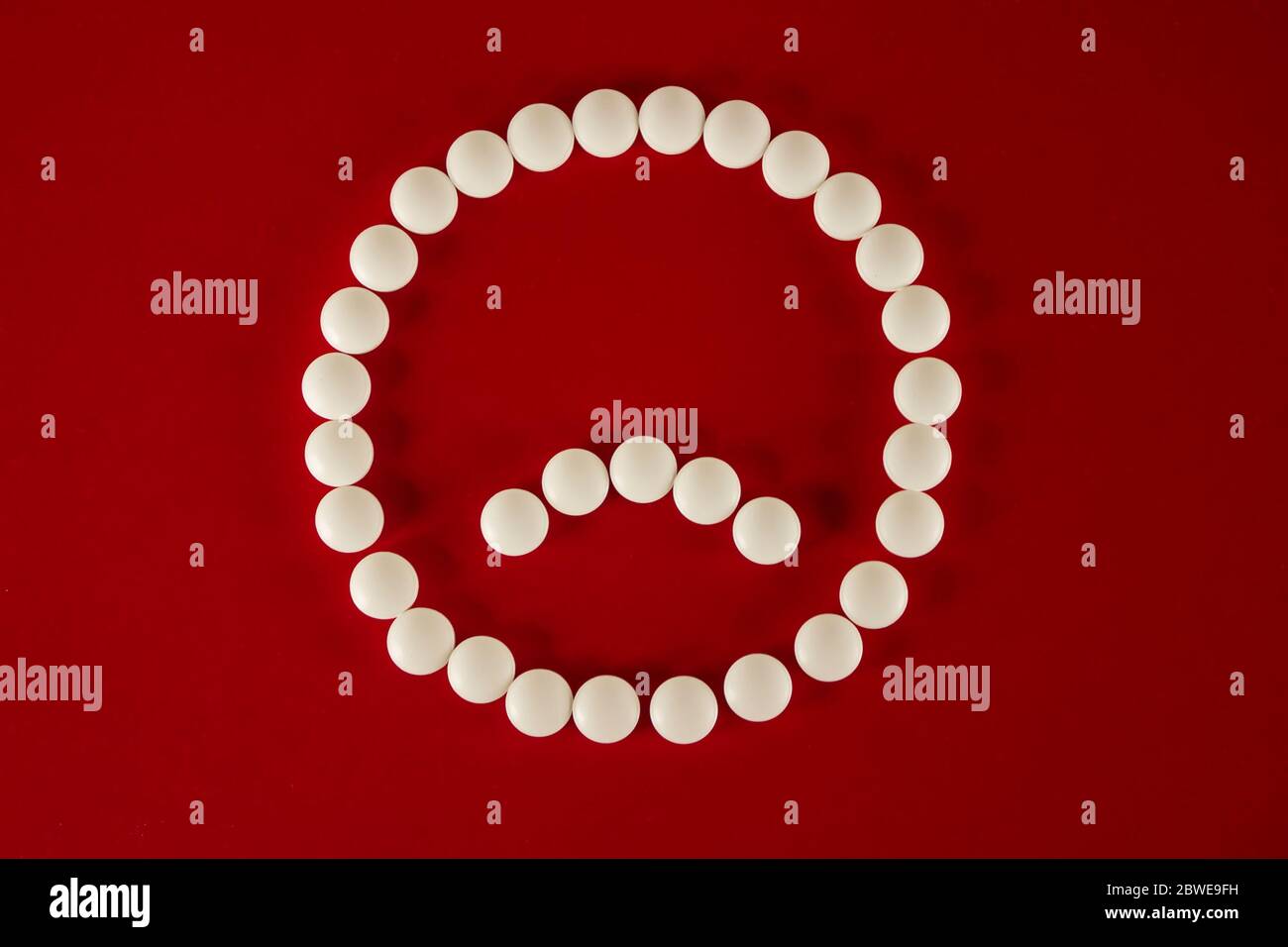 Traurig Smiley Gesicht aus weißen Tabletten und Pillen auf rotem Hintergrund Draufsicht gemacht. Stockfoto