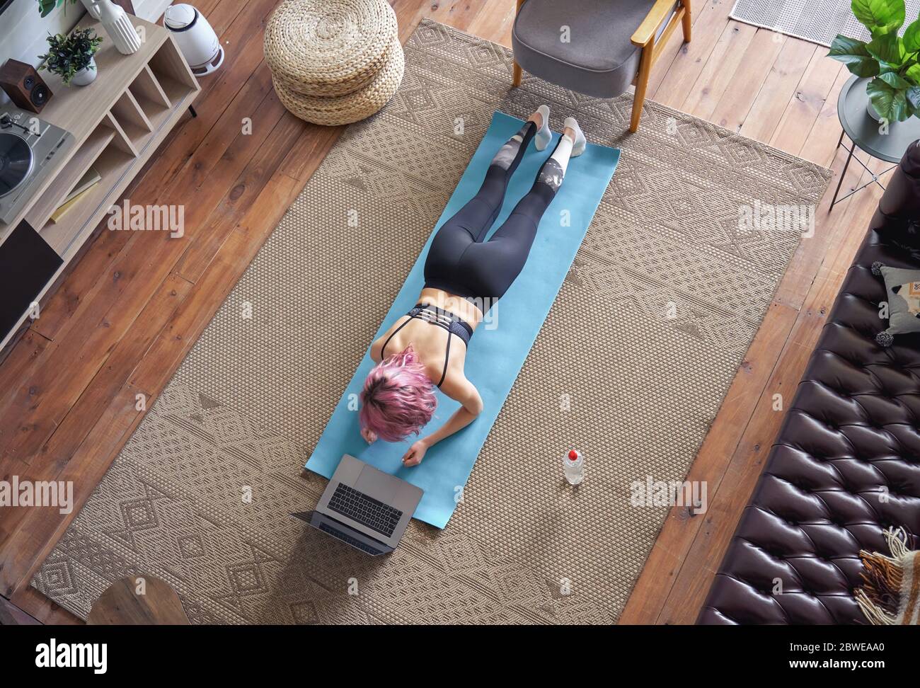 Sportliche Passform Frau rosa Haar tun Plank beobachten Online-Klasse zu Hause, Draufsicht. Stockfoto