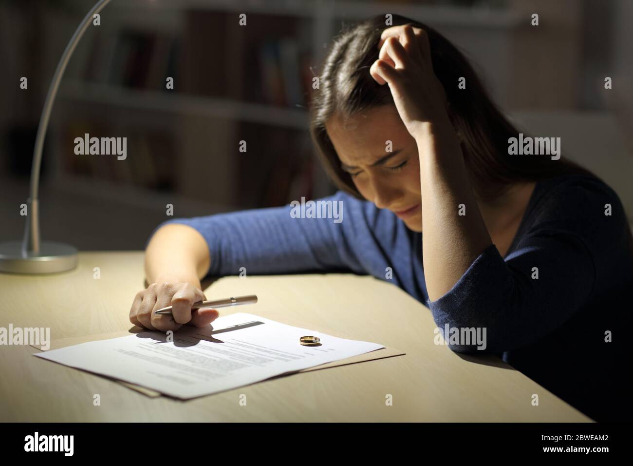 Traurige Frau beschwert sich Unterzeichnung Scheidung Papiere mit Ehering auf dem Tisch sitzen in der Nacht zu Hause Stockfoto