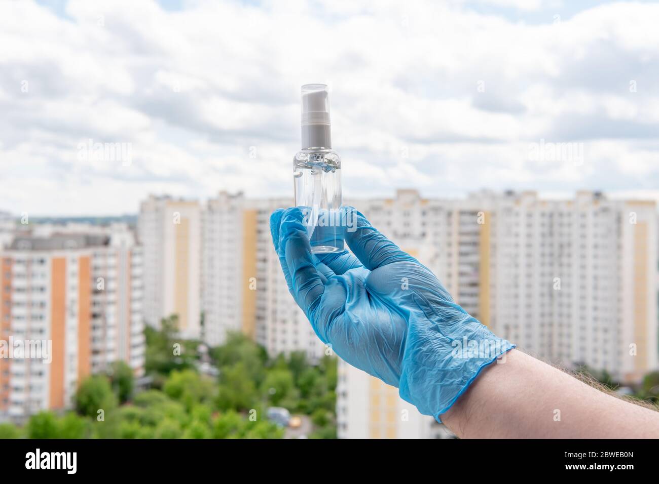 Männliche Hand in medizinischen Handschuh hält antiseptisches Gel auf Stadtbild Stockfoto