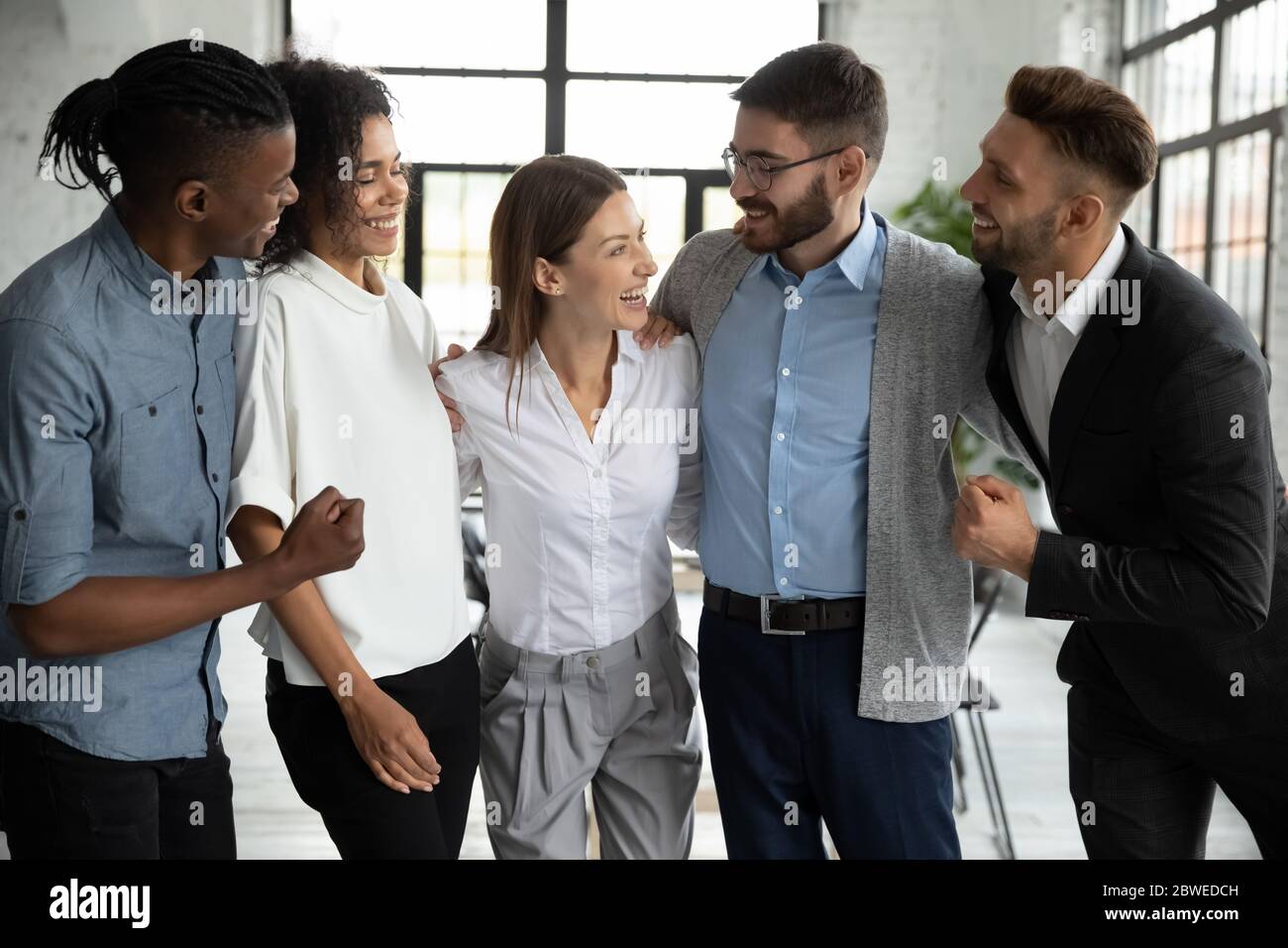 Glücklich verschiedene Mitarbeiter Team feiert Erfolg, Umarmung mit Teamleiter Stockfoto