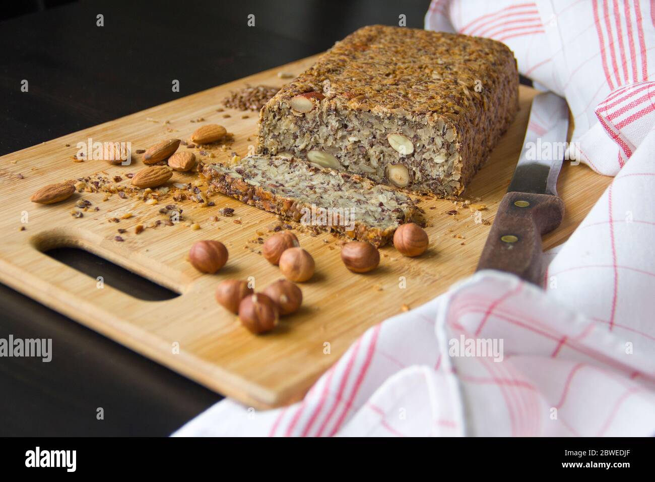Gesundes selbstgebackenes Keto-Brot mit Mandeln, Haselnüssen, Sonnenblumenkernen, Chiasamen auf einem Holzschneidebrett. Stockfoto