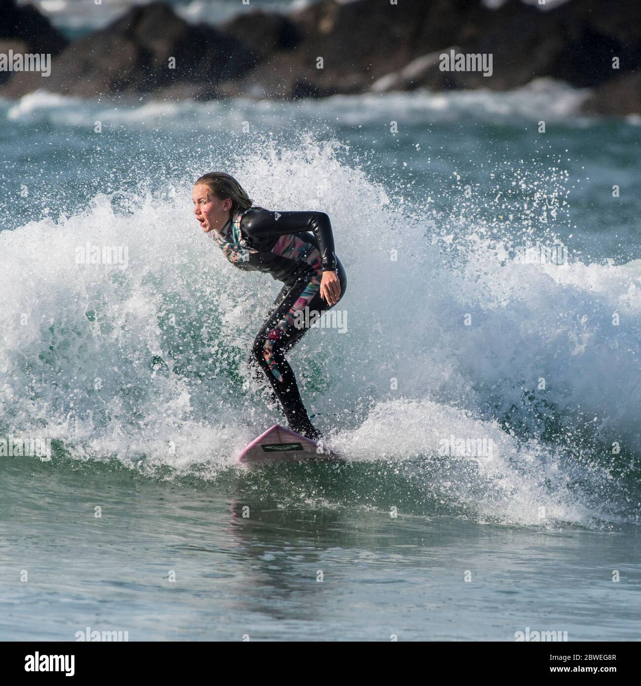 Spektakuläre surfen Aktion als eine junge weibliche Surfer reitet eine Welle an Fistral in Newquay in Cornwall. Stockfoto