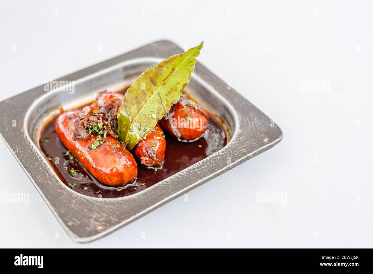 Bratpfanne mit leckeren gegrillten Würstchen auf dem Tisch. Gastronomie kulinarische Vorspeise in Metallpfanne zubereitet Stockfoto