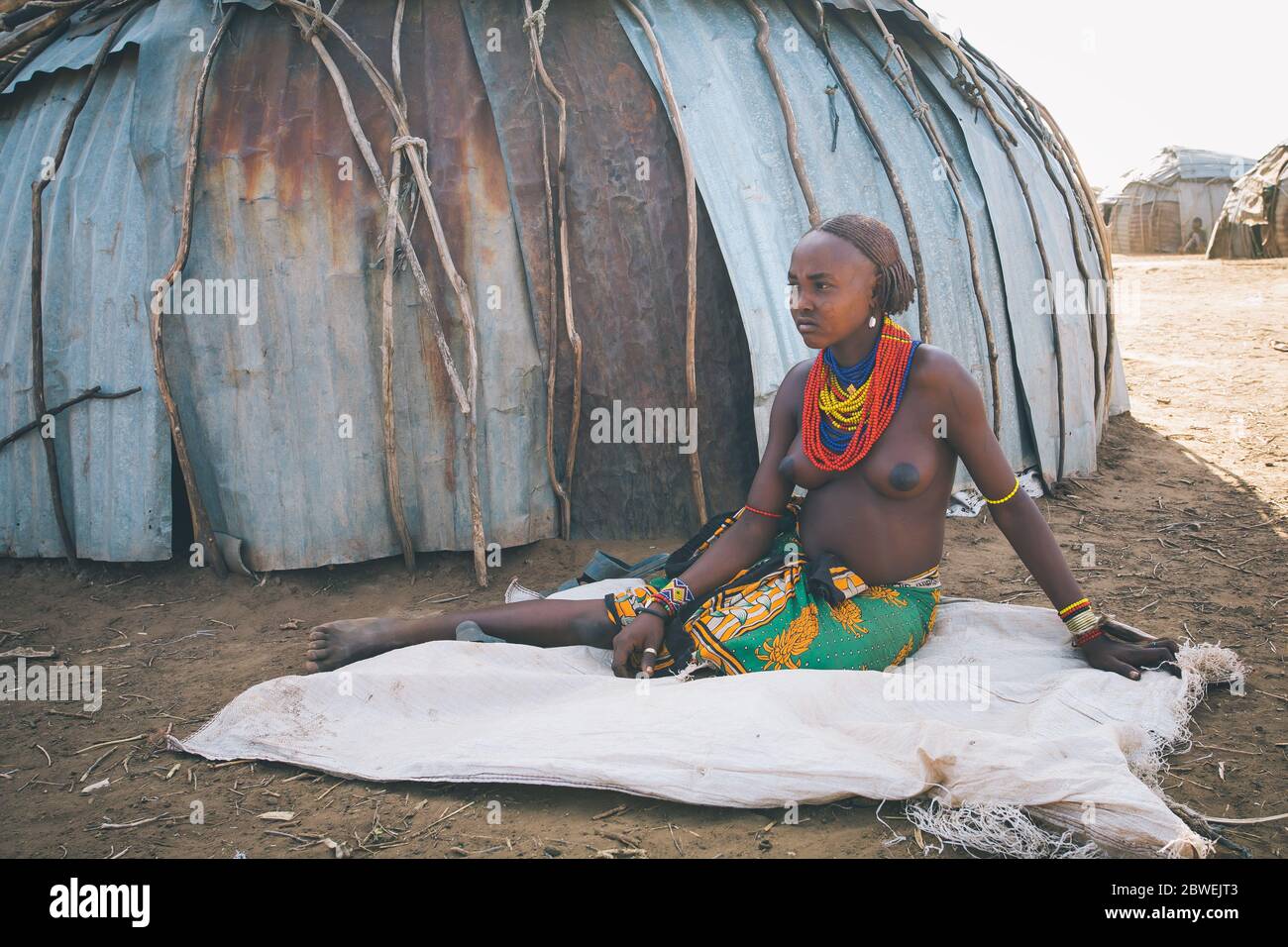 Omorate, Omo Valley, Äthiopien - 11. Mai 2019: Frau aus dem afrikanischen Stamm Dasanesh, die im Schatten einer Hütte ruht. Daasanach sind die Cushitic ethnischen Gruppe inha Stockfoto