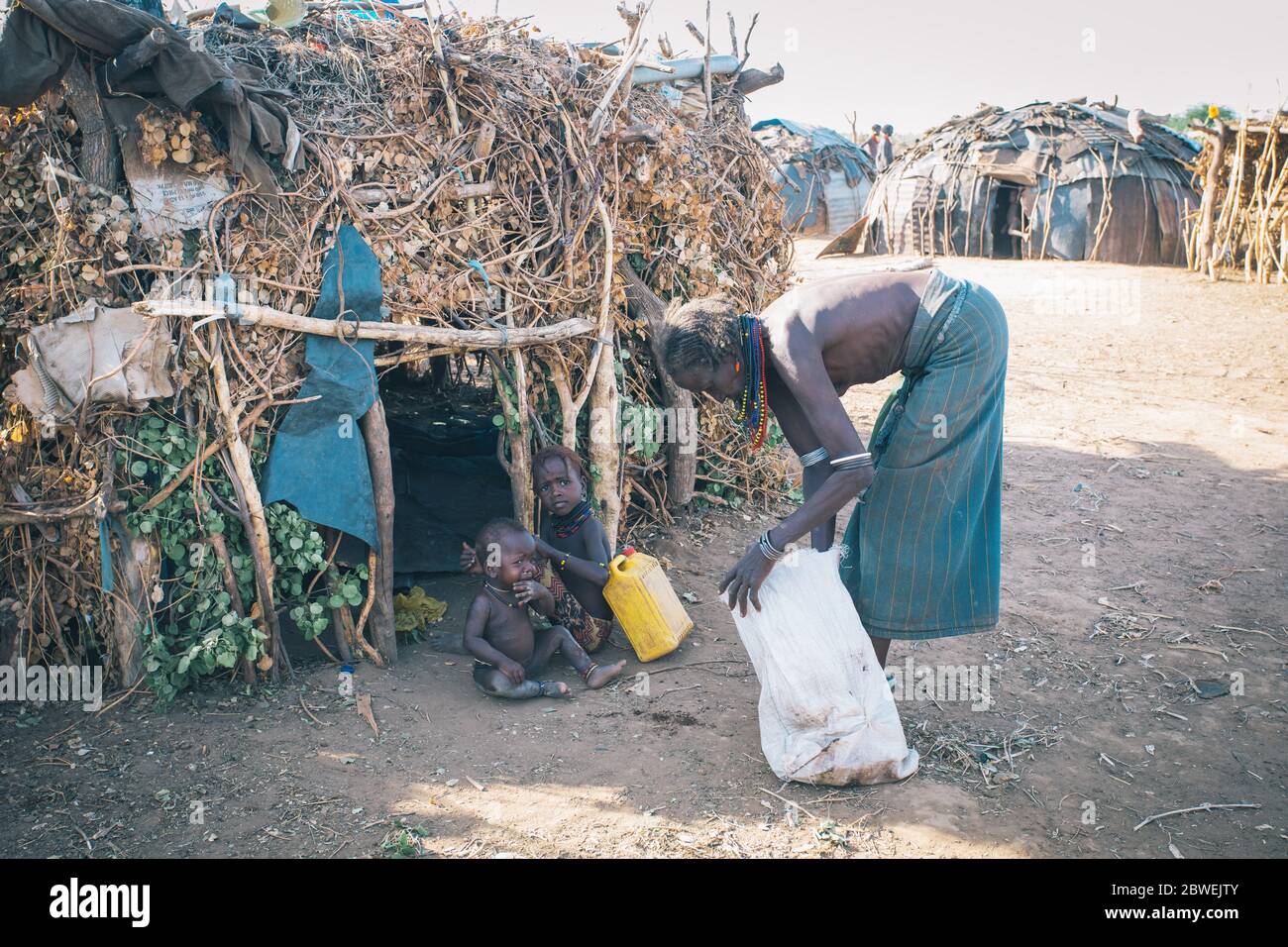 Omorate, Omo Valley, Äthiopien - 11. Mai 2019: Frau aus dem afrikanischen Stamm Dasanesh mit Kindern vor seiner Hütte. Daasanach sind cushitic ethnischen g Stockfoto