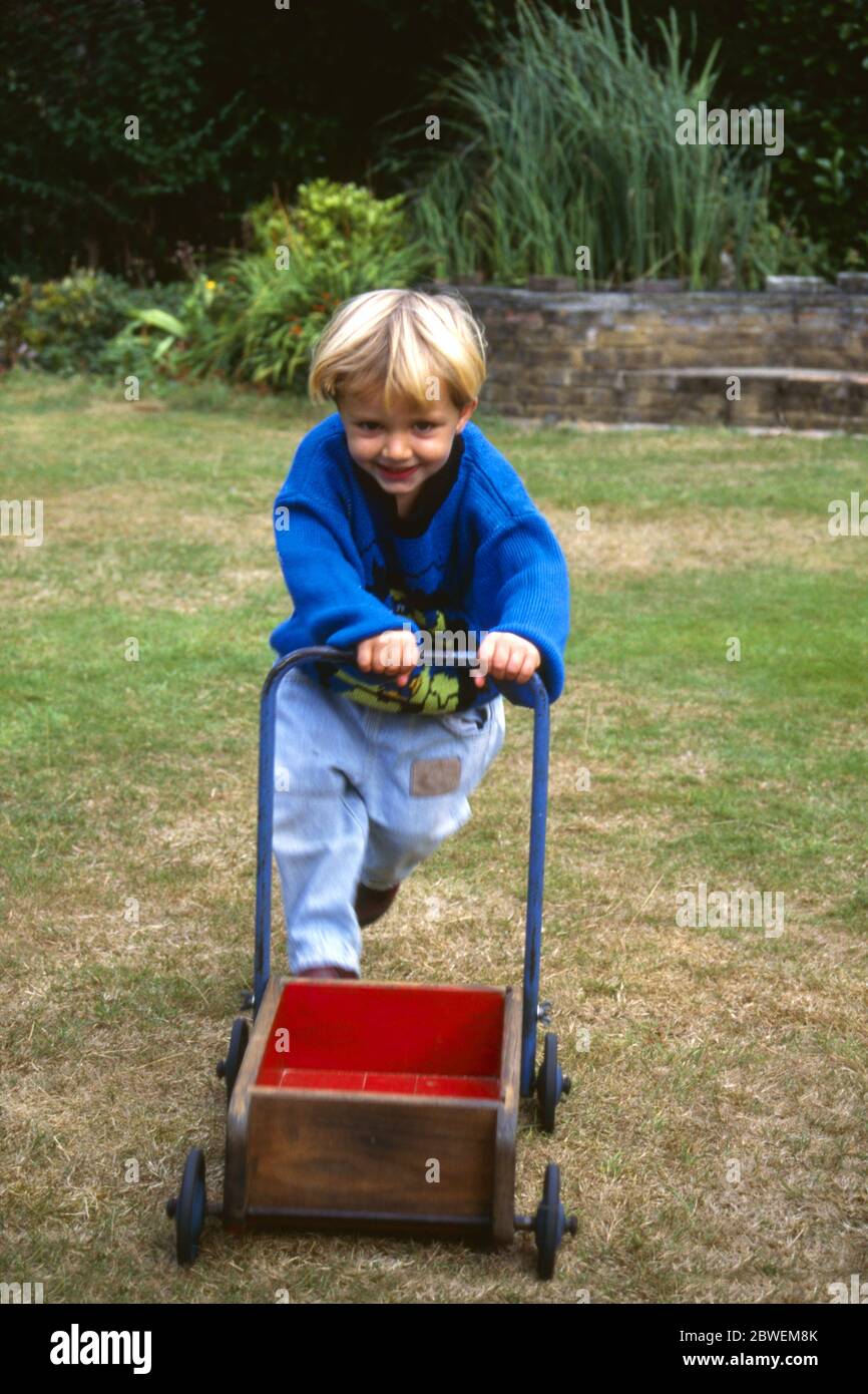 Kleiner Junge, 28 Monate alt, mit Baby Walker auf Gras im heimischen Garten, Kent, England Stockfoto