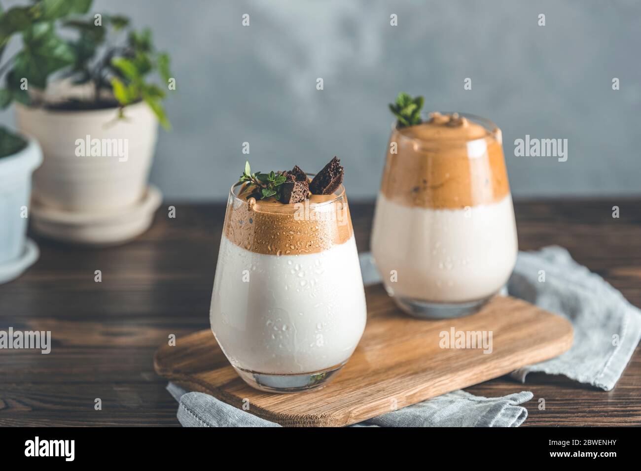 Zwei Gläser mit Wassertropfen von Dalgona schaumig Kaffee Trend koreanischen Drink Latte Espresso mit Kaffeeschaum, von Thymian und dunkler Schokolade dekoriert. Dunkel Stockfoto