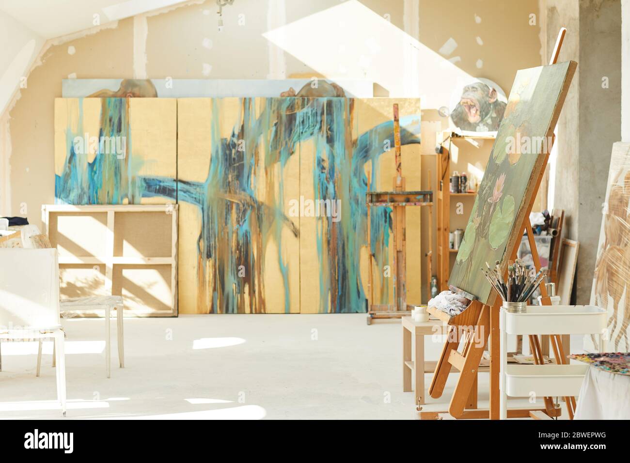Hintergrundbild von leeren Kunststudio im Dachboden von Sonnenlicht beleuchtet, Fokus auf Staffelei und abstrakte Gemälde, kopieren Raum Stockfoto