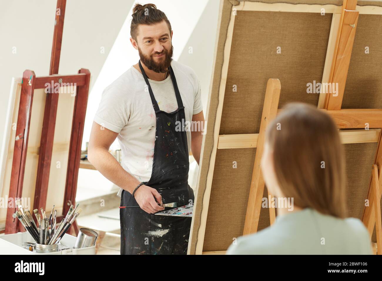 Porträt von fröhlichen bärtigen Künstler Malerei Porträt der jungen Frau im Studio, Kopie Raum Stockfoto