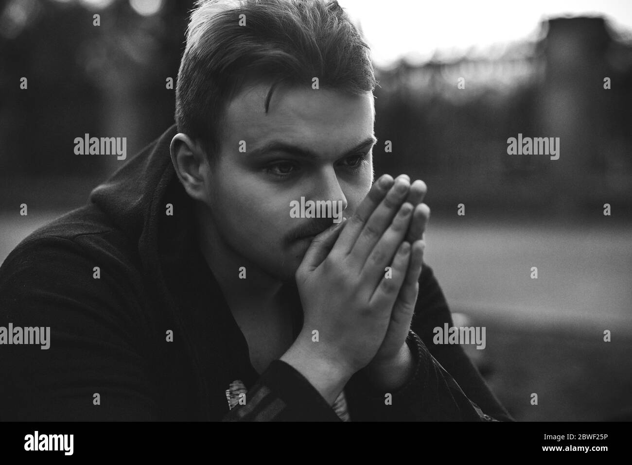 Porträt eines traurigen, depressiven Mannes, der allein auf der Straße sitzt Stockfoto