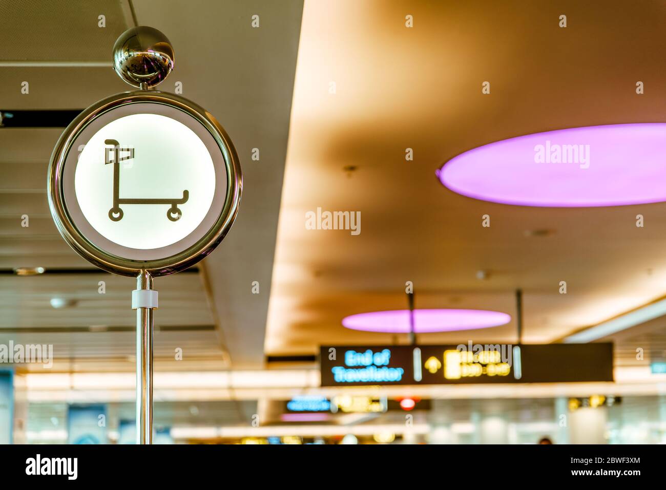 Beleuchtetes Schild mit Gepäckwagen, Trolleys für Gepäck. Bequeme Art des Gepäcktransports am Flughafen Stockfoto