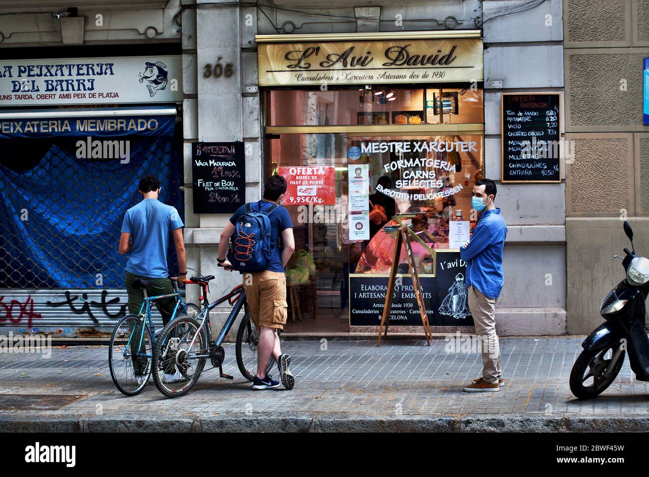 Drei junge Männer warten auf einen Feinkostladen in Barcelona, Spanien. Stockfoto