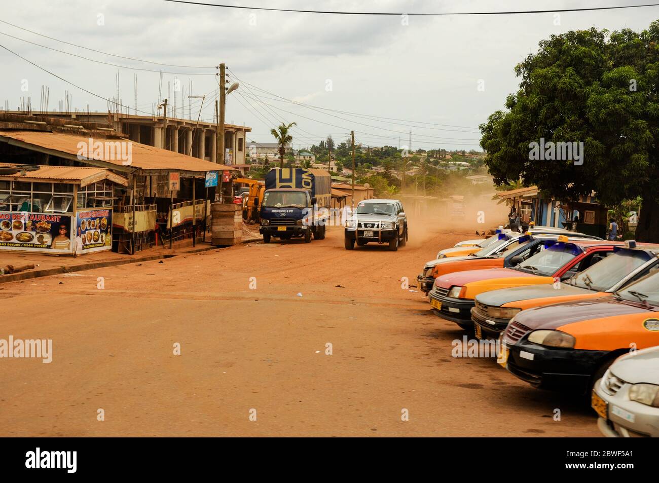 Eine Schotterstraße, die durch ein armes afrikanisches Dorf führt - Accra, Ghana, Afrika Stockfoto