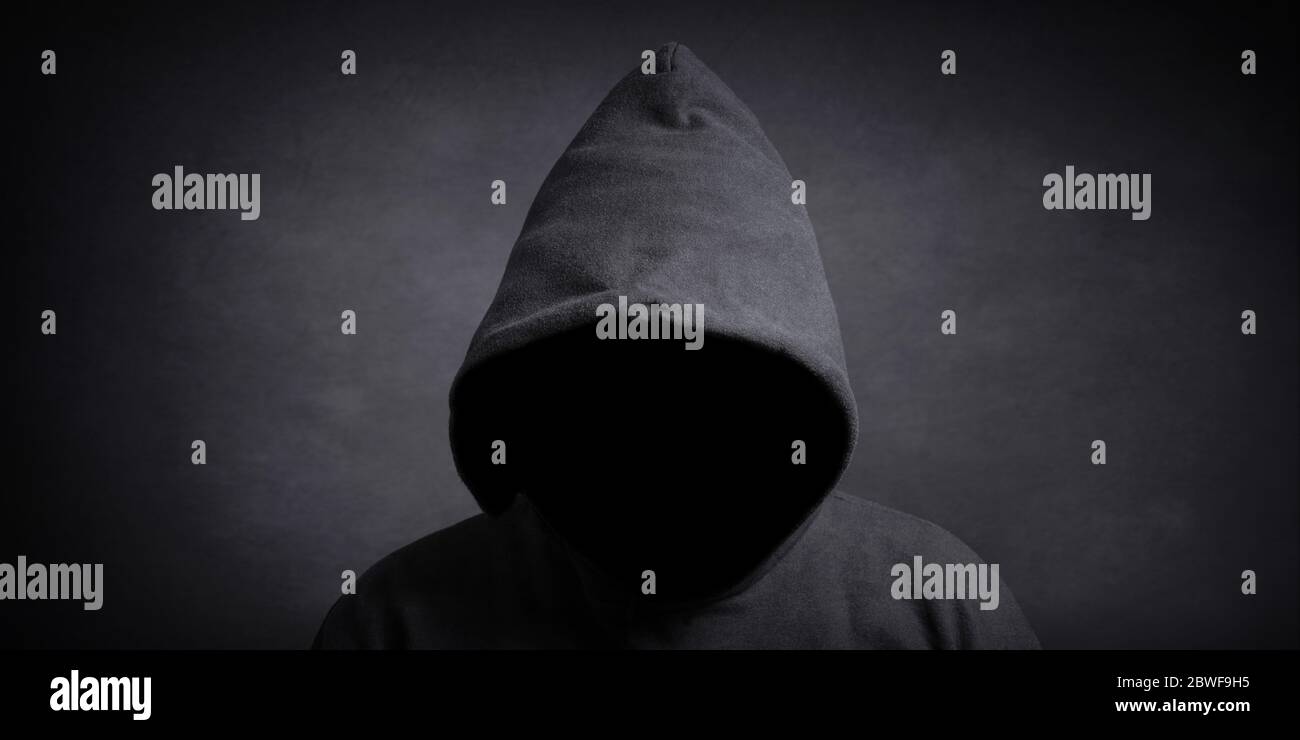 Gesichtslose Person trägt schwarzen Hoodie versteckt Gesicht im Schatten - Geheimnis Verbrechen Verschwörung Konzept Stockfoto