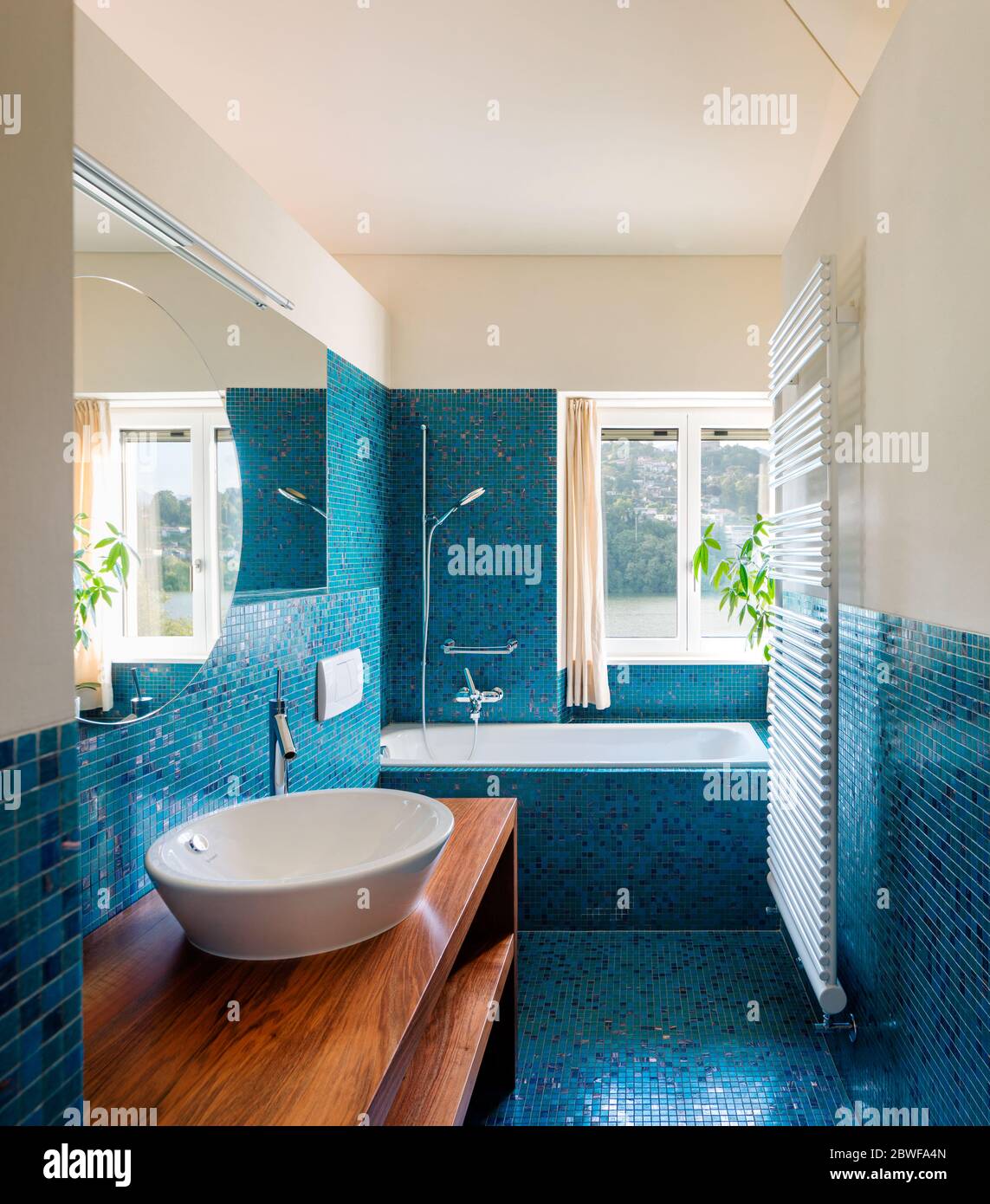 Modernes blaues Badezimmer mit Blick auf die Natur. Niemand im Inneren ist sehr leer. Warmes Licht Stockfoto
