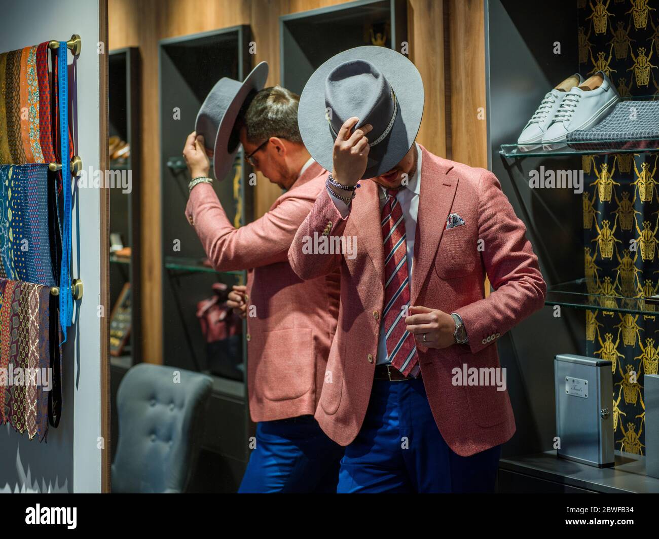 Mann in Anzug versteckt Gesicht hinter seinem Hut Stockfoto