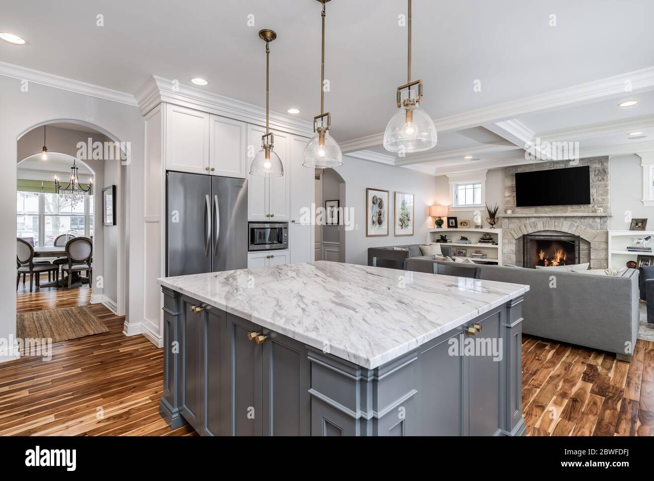 Eine luxuriöse, weiße Küche mit einer Granitplatte und einem gefliesten Backsplash hinter dem Edelstahl KitchenAid Herd. Stockfoto