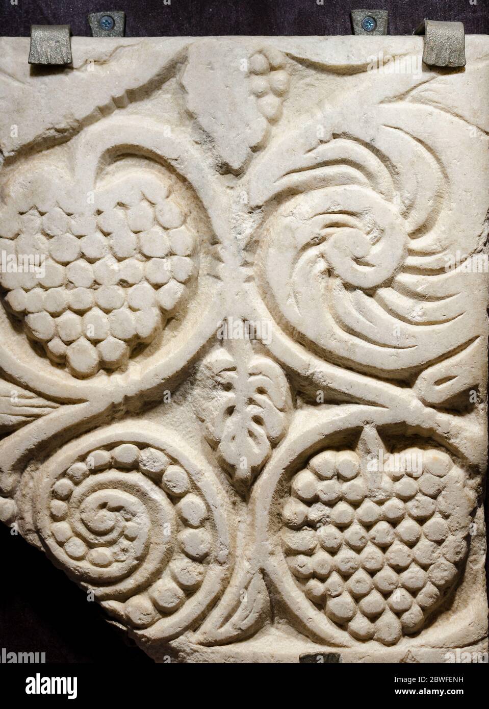 Traubenförmige romanische Dekorationen in der Steinmauer einer alten mittelalterlichen Kirche geschnitzt Stockfoto