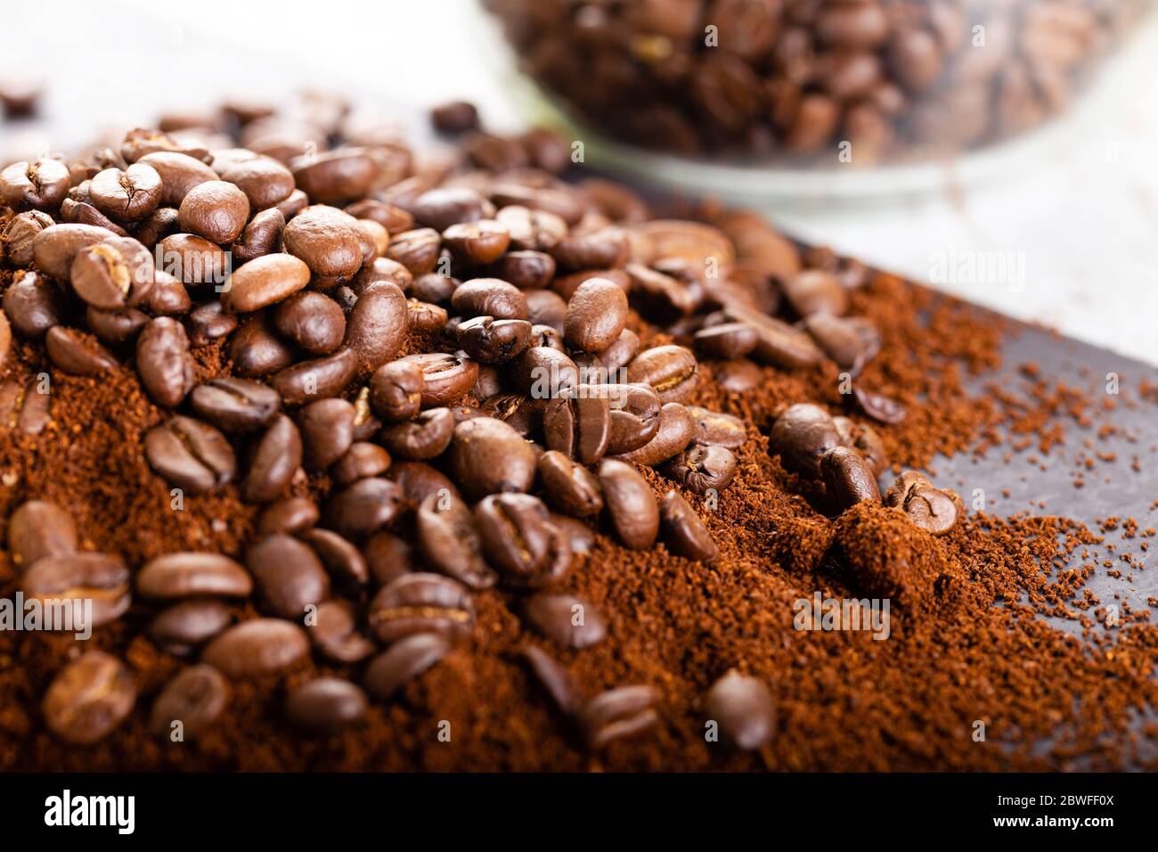 Kaffeebohnen und Kaffeesatz aus nächster Nähe. Hintergrund. Kaffeebohnen in einem Glasgefäß im Hintergrund. Stockfoto