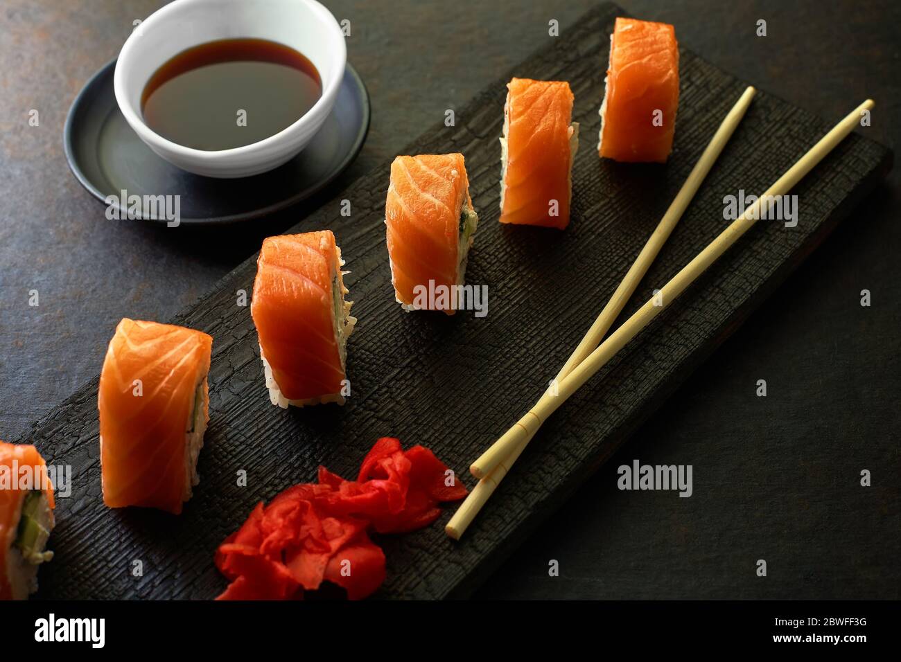 Sushi-Brötchen. Dunkler Stil. Serviert eine Mahlzeit in einem japanischen Restaurant. Draufsicht mit Platz zum Kopieren. Minimalismus im Marketing Stockfoto