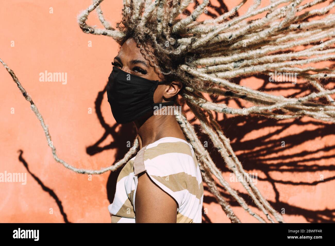 Porträt von afrikanischen Mädchen bewegen blonde Dreadlocks Haar tragen Gesicht Schutzmaske für Coronavirus Prävention - Covid 19 Lifestyle und trendy Menschen c Stockfoto