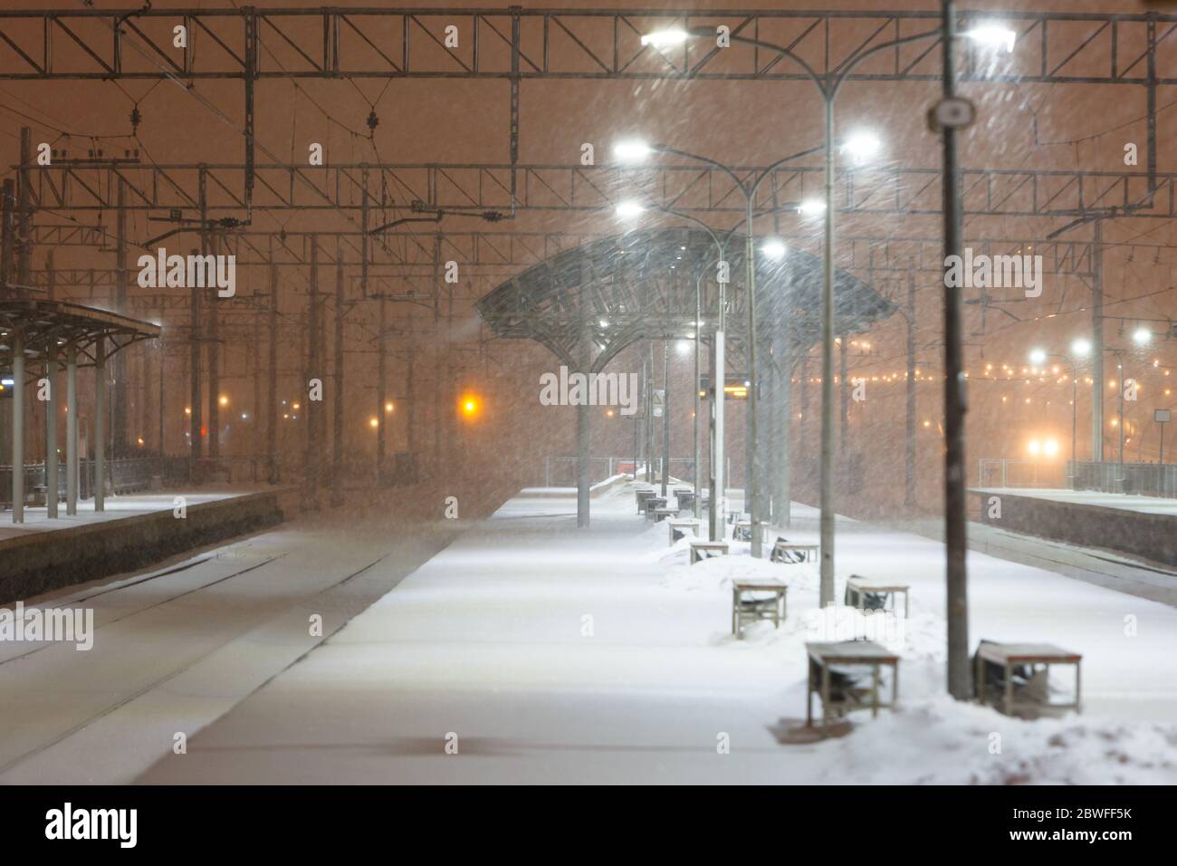 Leerer Bahnsteig ohne Passagiere im Schneesturm/starkem Schneefall in der Nacht. Eisenbahn, schlechtes Wetter Stockfoto