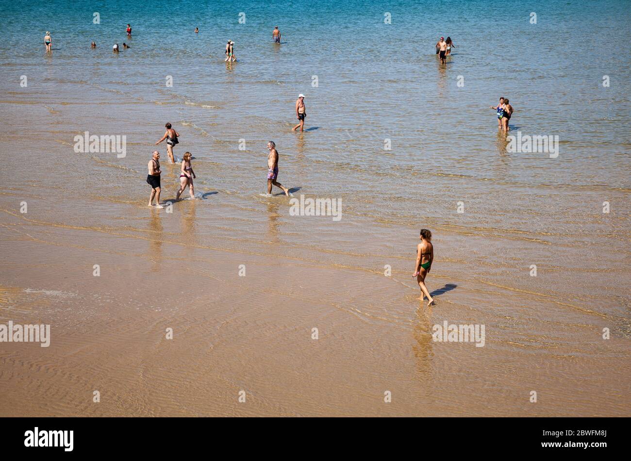 An einem sonnigen Tag paddeln, schwimmen und bummeln die Leute am Strand von San Sebastian Stockfoto