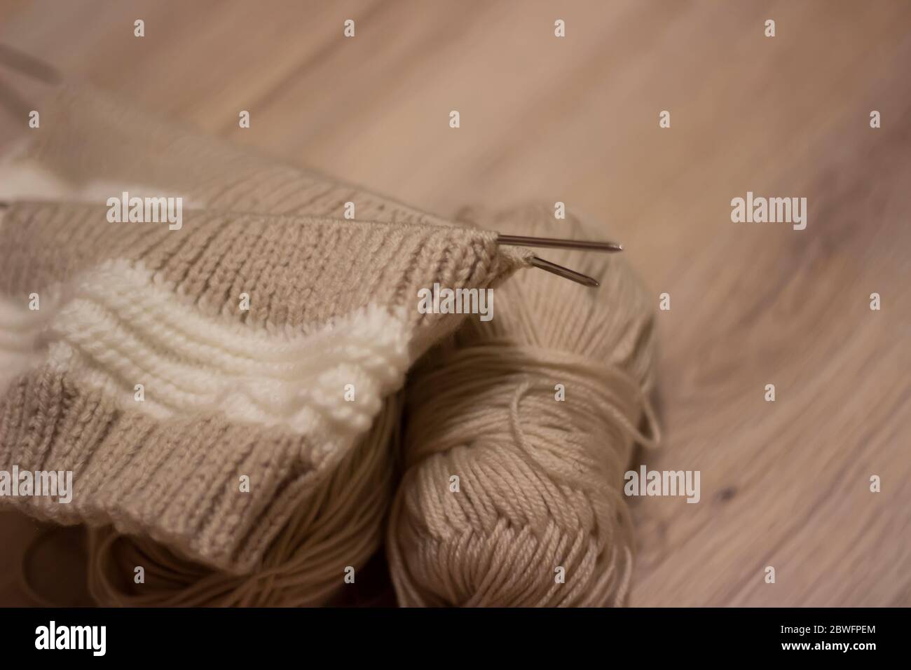Braun stricken auf hellem Hintergrund.Stricknadeln und Skeins aus Wolle, Handstricken. Selektiver Fokus. Stockfoto