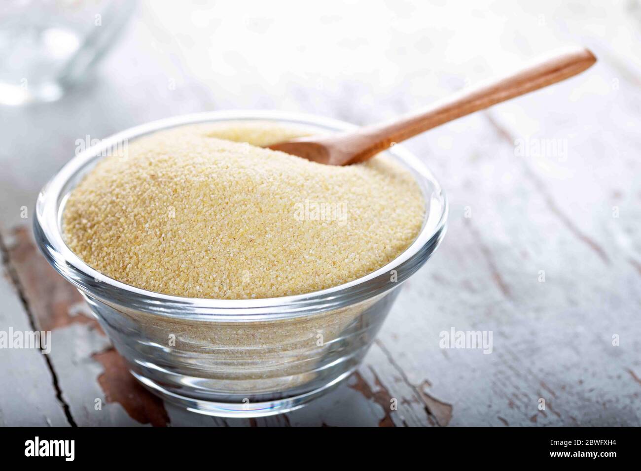 Grieß in Glasschüssel mit Löffel auf Holzhintergrund. Stockfoto