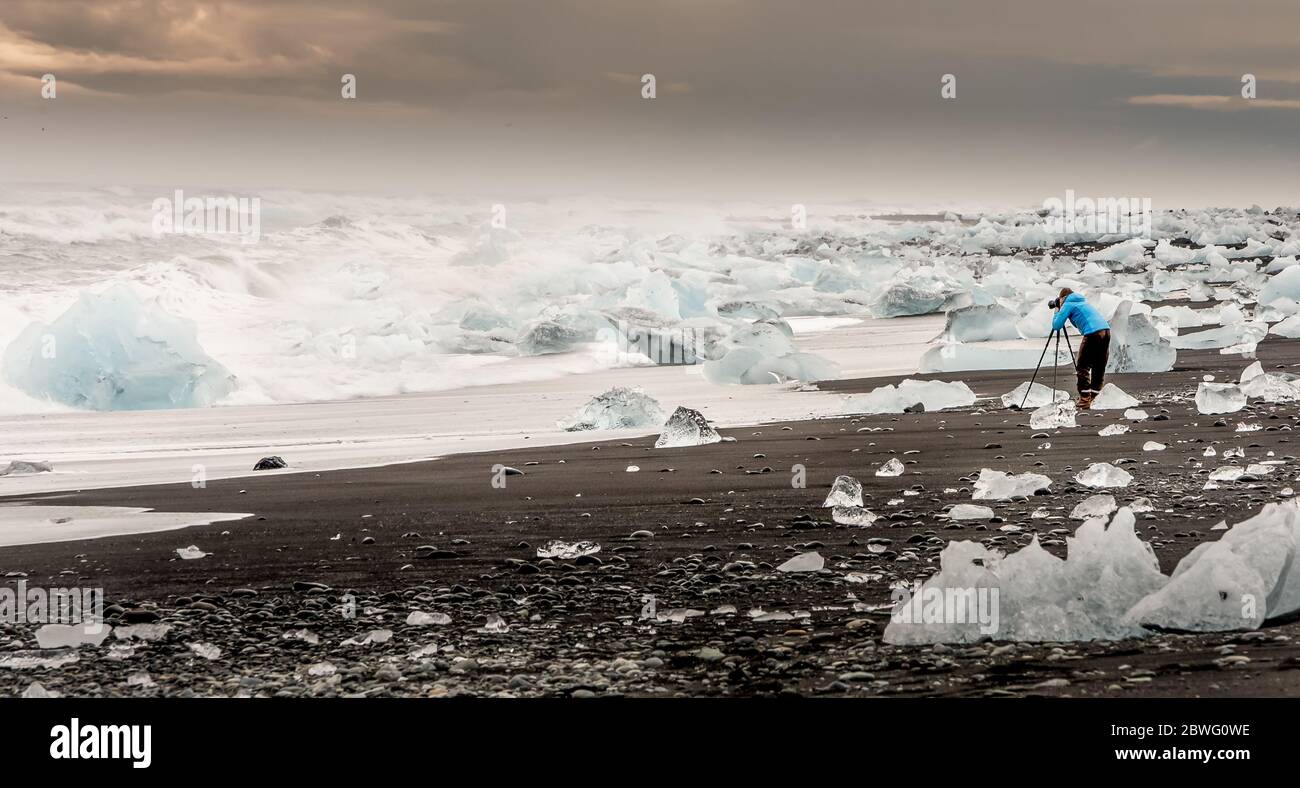 Unanerkannter Fotograf, der die Eisbrocken vom vatnajokull Gletscher während des Sonnenuntergangs in Island einfängt Stockfoto