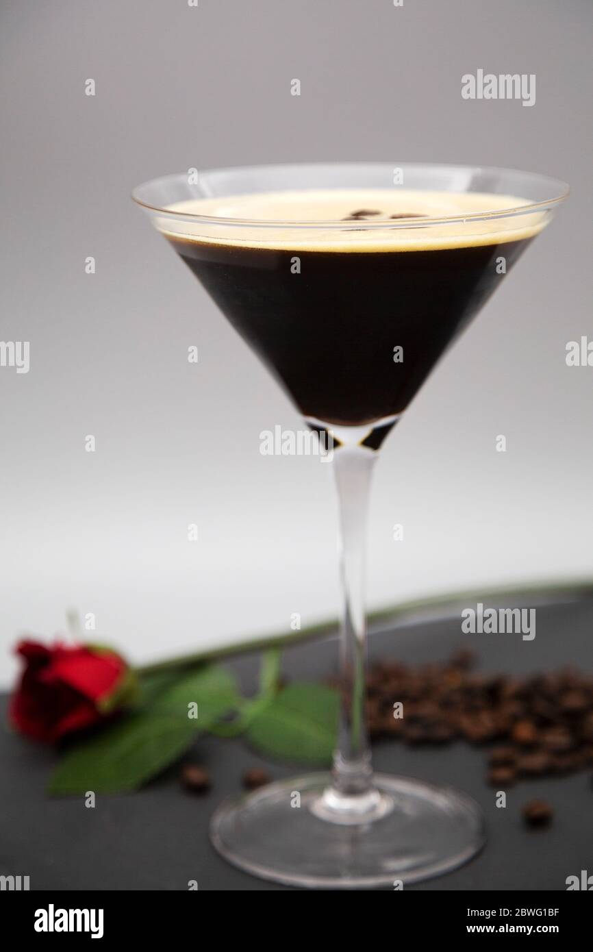 Ein Espresso Martini in einem martiniglas serviert und mit gerösteten Kaffeebohnen garniert. Das Glas wird mit frisch gerösteten Kaffeebohnen gesehen. Stockfoto