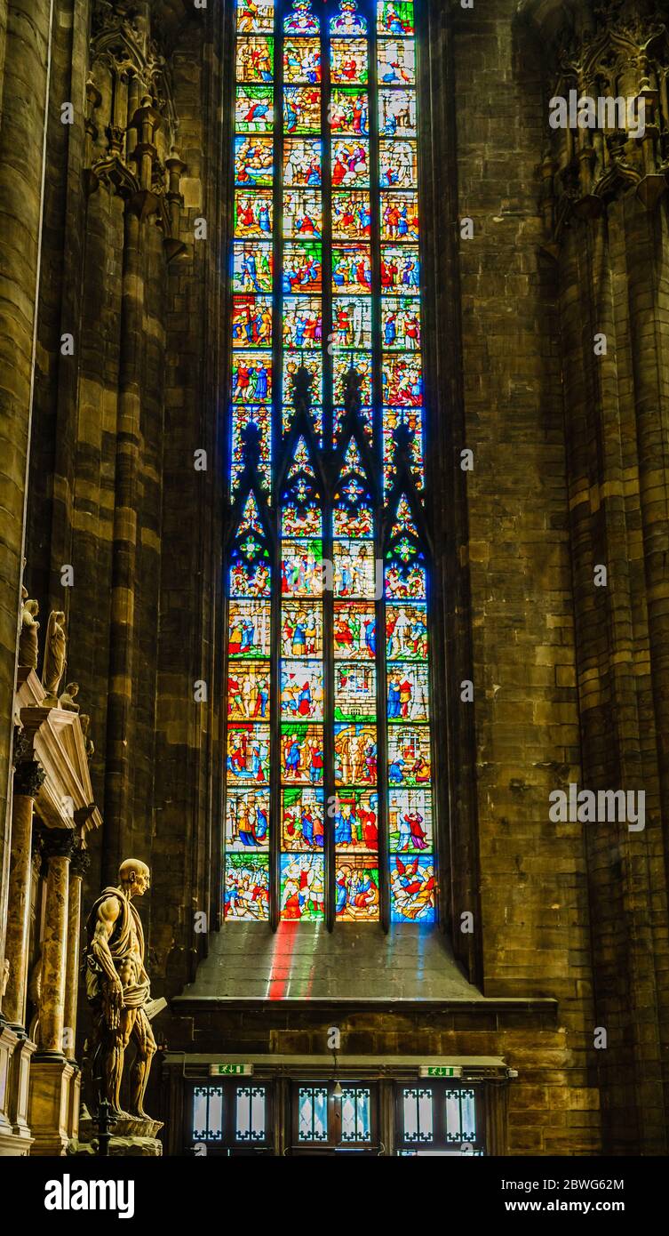 Mailand, Lombardei, Italien - April 2019: Statue des hl. Bartholomäus im Inneren der Mailänder Kathedrale mit bunten religiösen Glasfenstern im Hintergrund Stockfoto